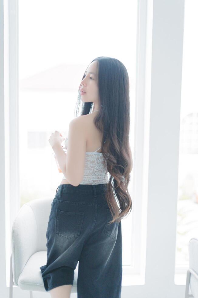 Young Woman Posing by Window with Long Hair and Casual Attire photo