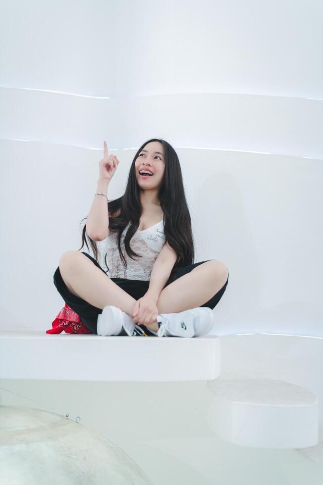 A woman sitting on a white platform with her hand up photo