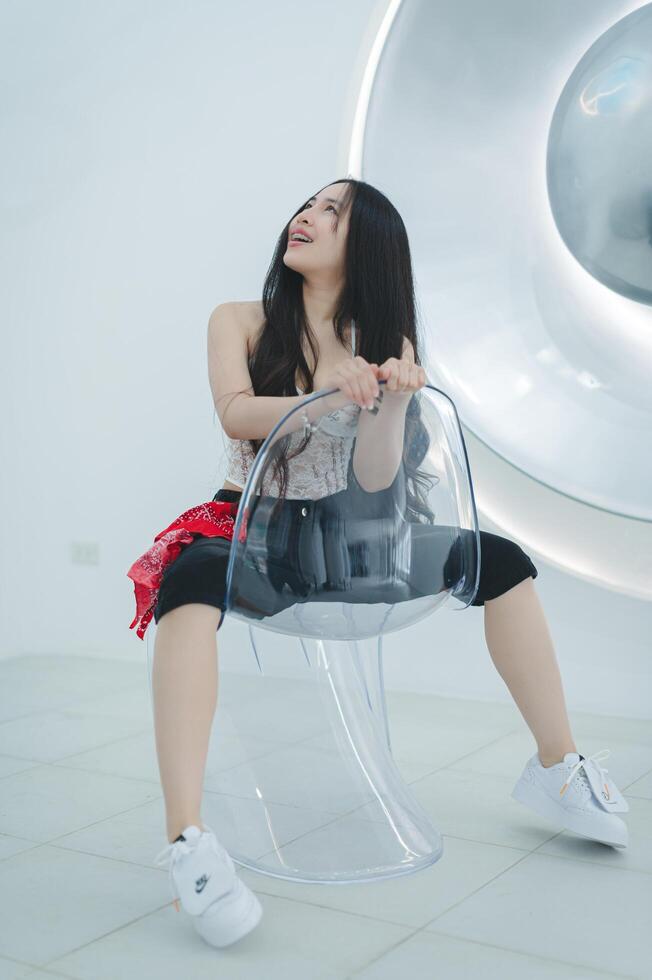 Young Woman Sitting on Transparent Chair in Modern Minimalist Room photo