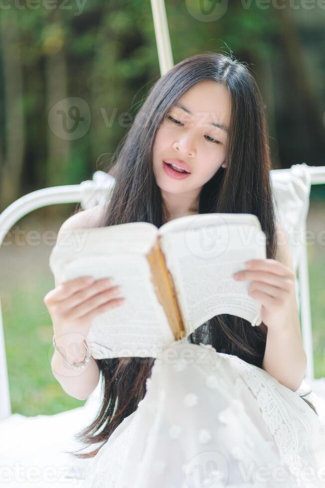 Young Woman Reading Book in Nature with Soft Light and Greenery photo