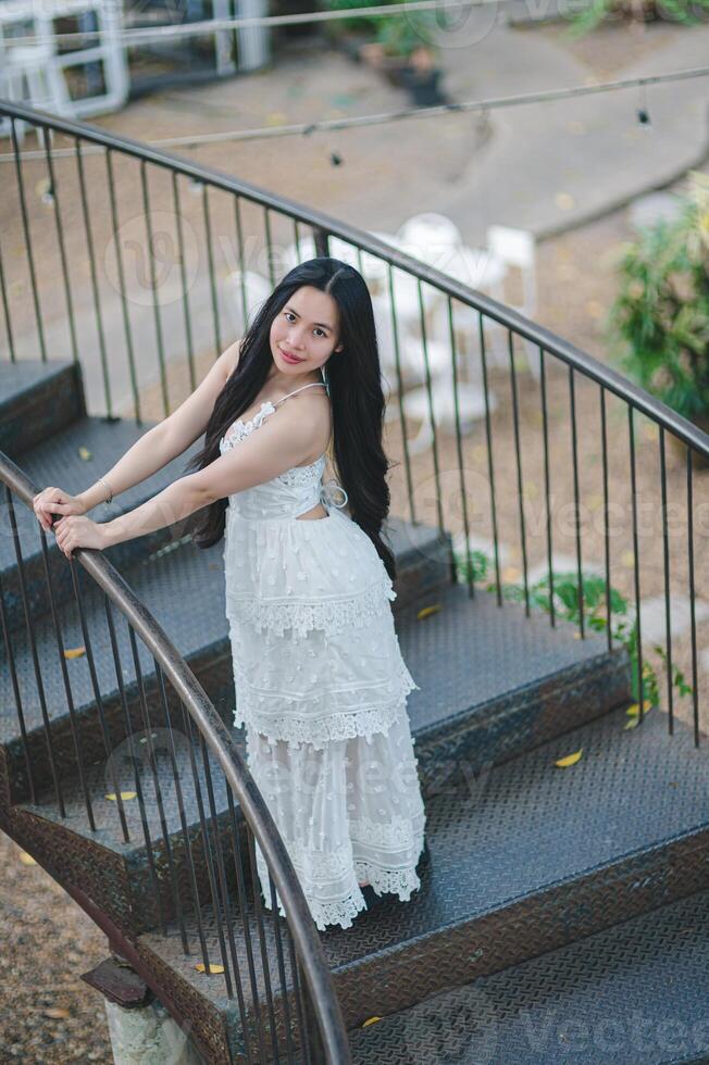 Elegant Young Woman White Dress Posing on Outdoor Spiral Staircase photo