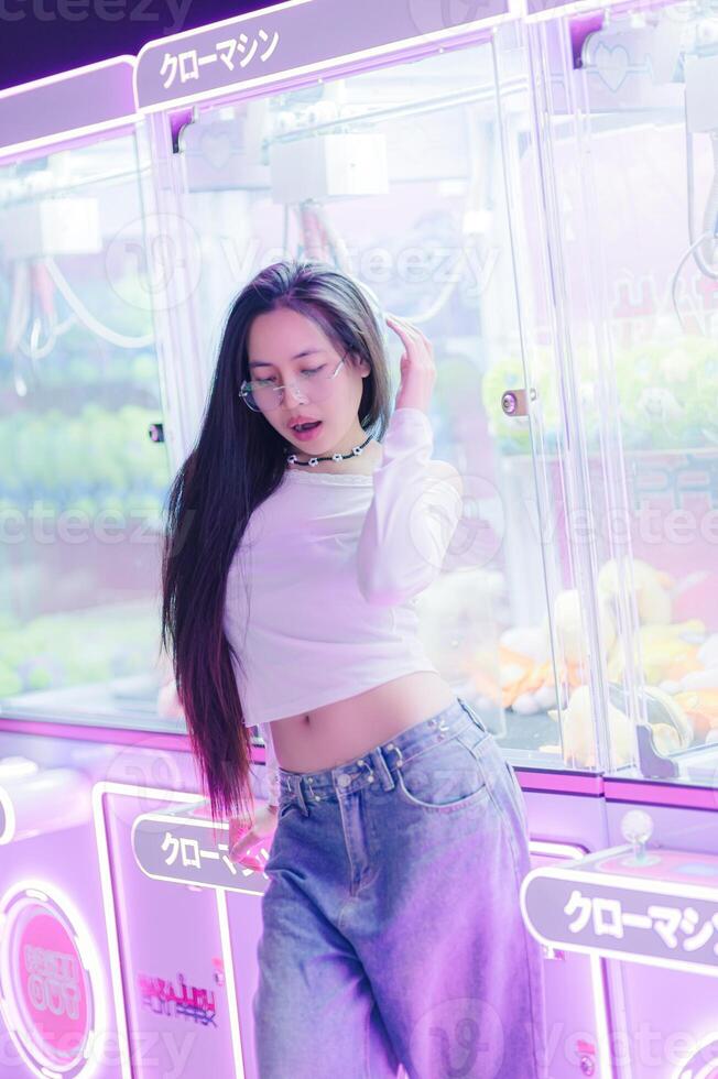 Young Woman Posing Near Colorful Arcade Claw Machine photo