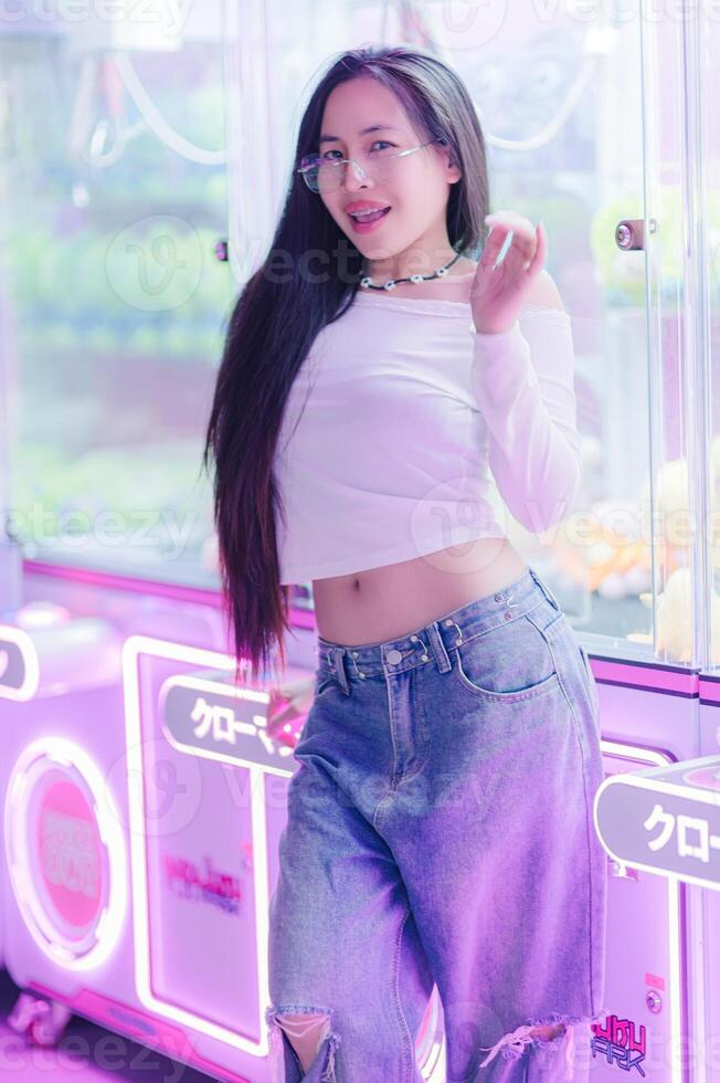 Playful Young Woman Posing in Neon Arcade Setting photo