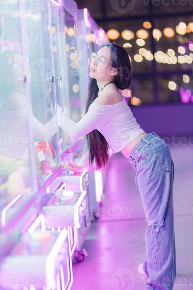 Young Woman Enjoying Game at Arcade with Neon Lights Behind Her photo
