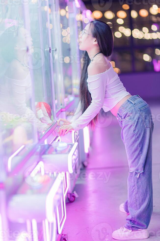 Young Woman in Casual Outfit Enjoying Arcade Game at Night photo