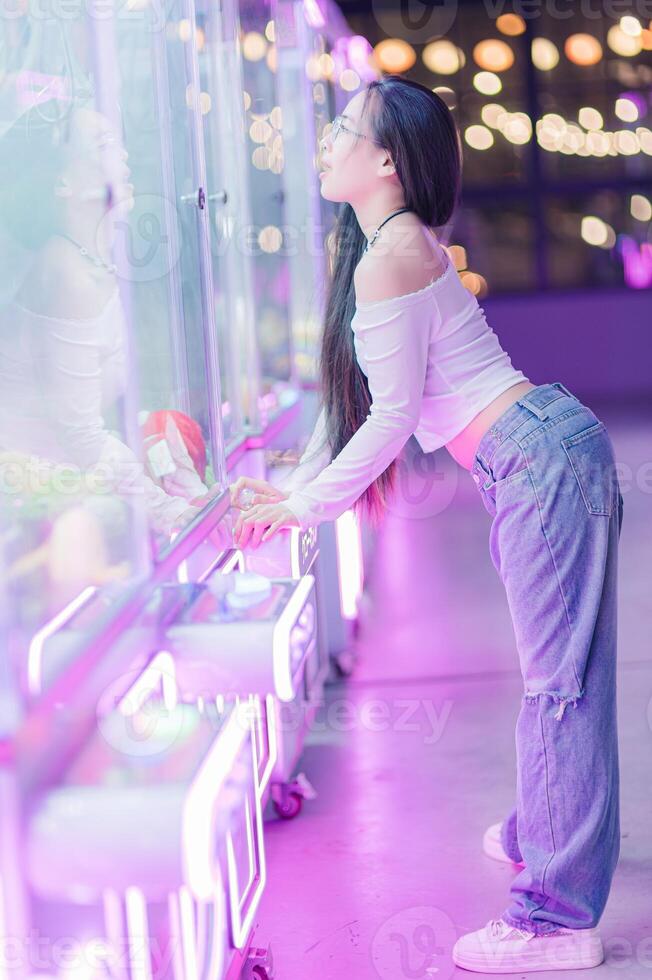 Young Woman Playing in Colorful Arcade with Neon Lights Glow photo