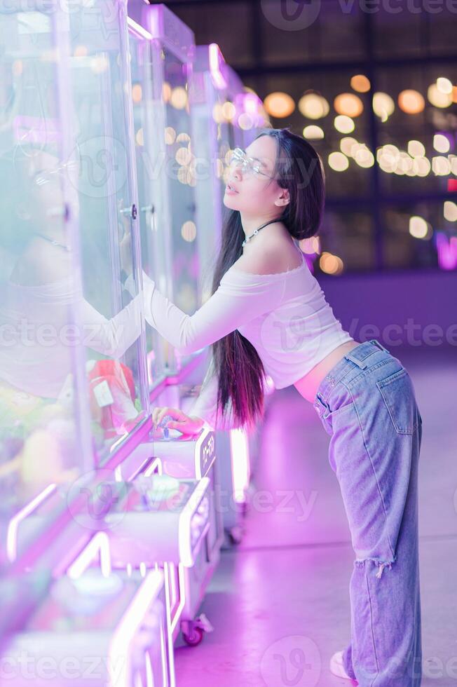 Young Woman Enjoying Vending Machine in Neon Setting with Plush Toys photo