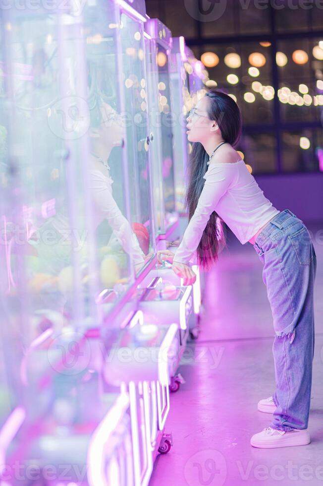 Young woman enjoys arcade game in colorful neon-lit environment photo