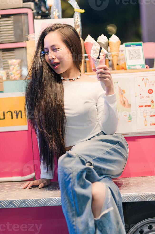 Woman Enjoying Ice Cream at Colorful Food Stall in City Night photo