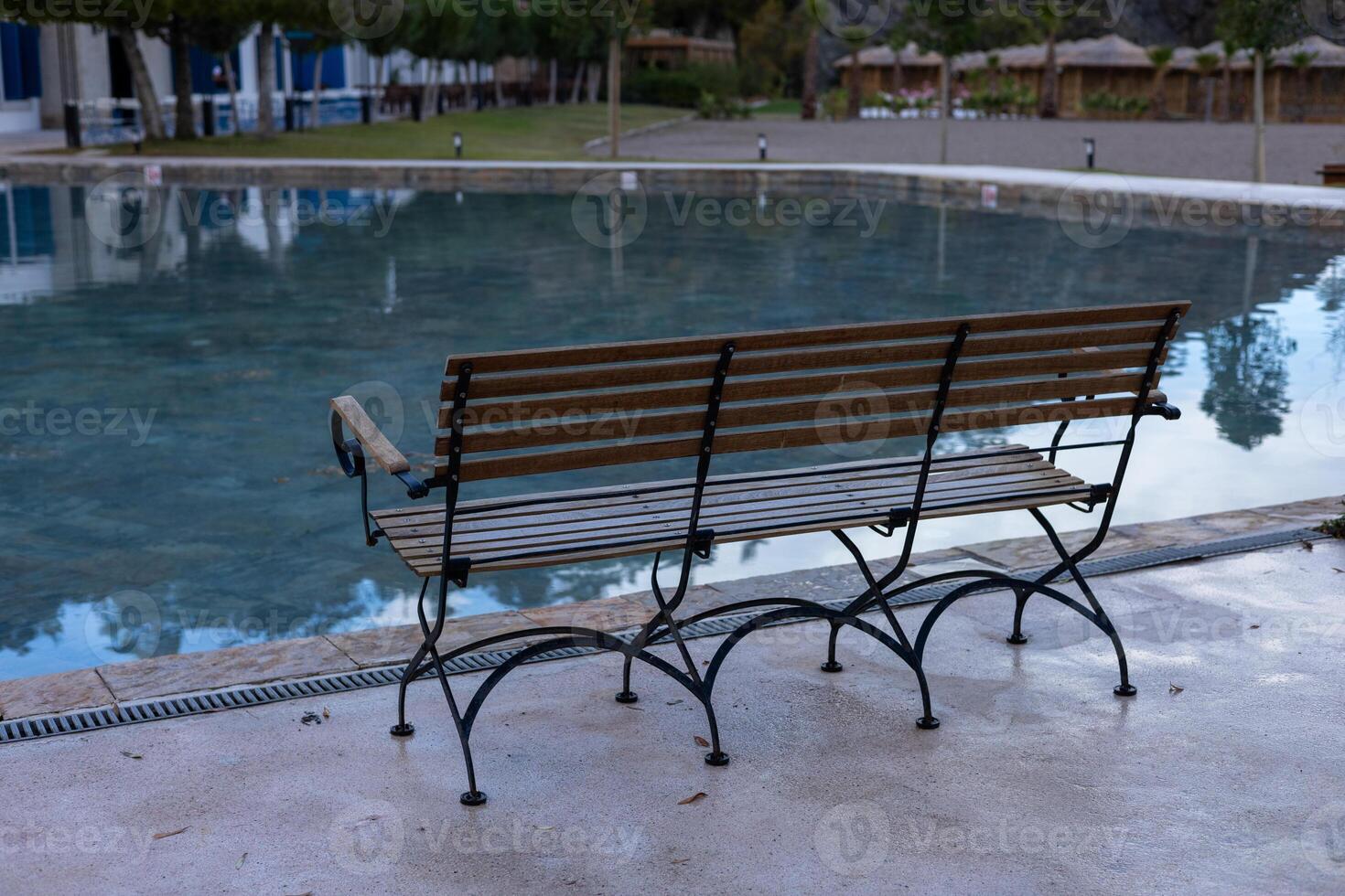 Quiet bench beside tranquil pool at a serene park in the late afternoon photo
