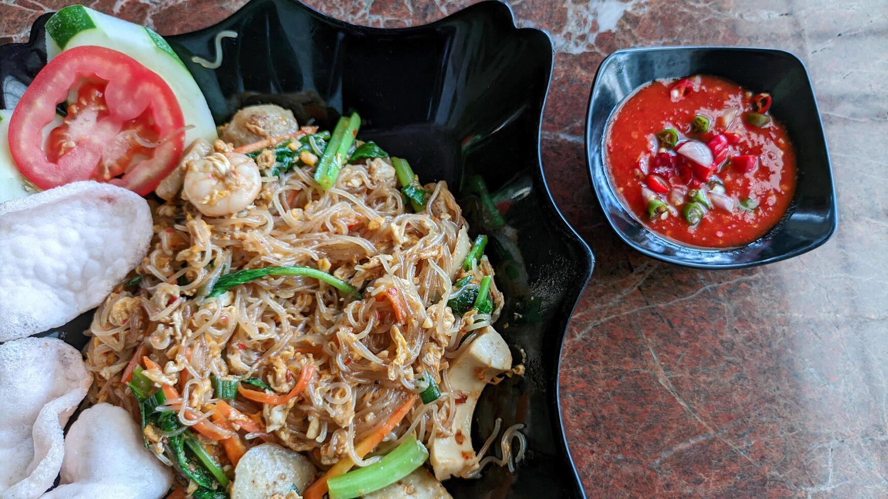 Close up of fried seafood vermicelli or bihun goreng with spicy tomato sauce is good for breakfast. photo