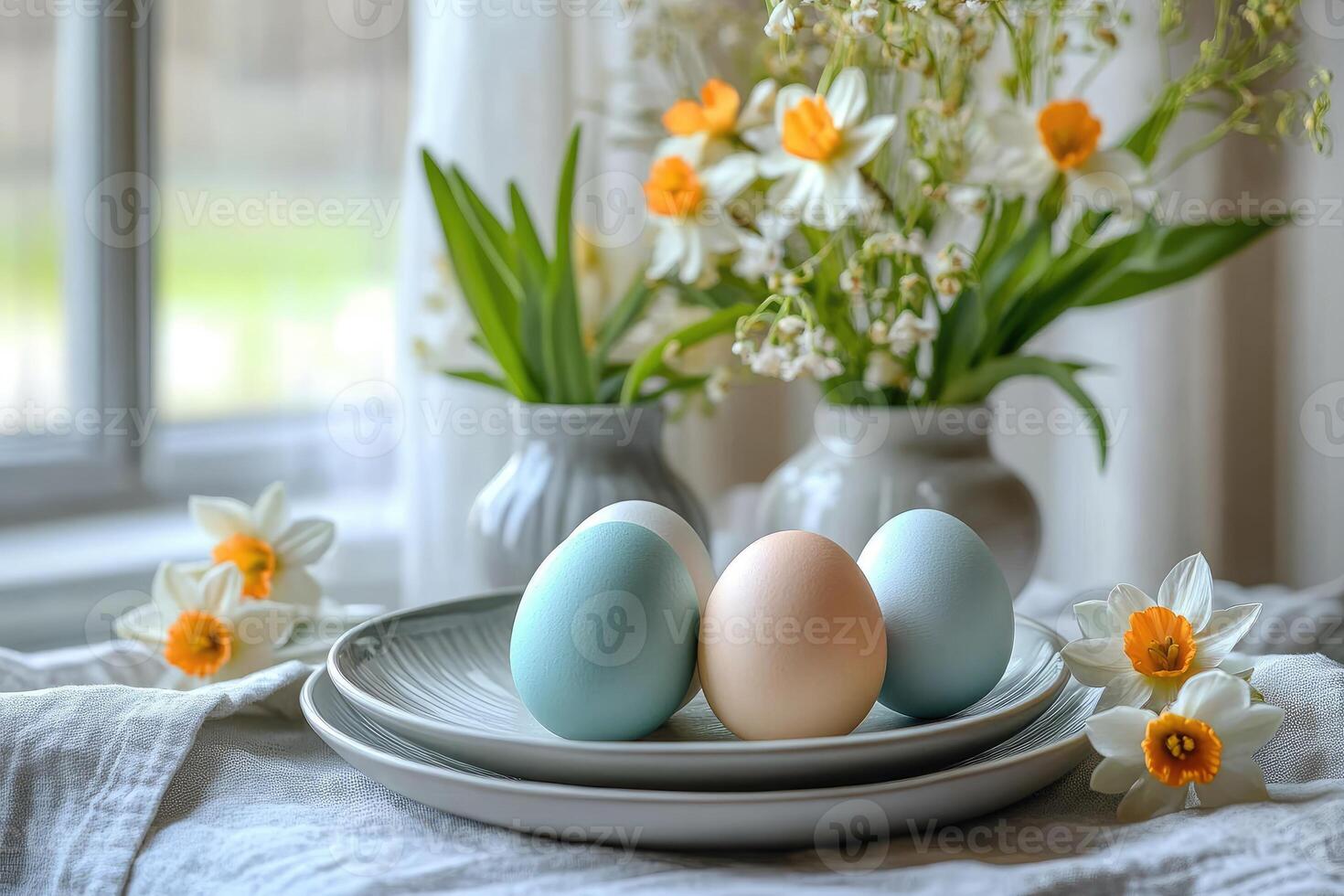 Easter eggs are laying on plates near daffodils and lilies of the valley in window photo