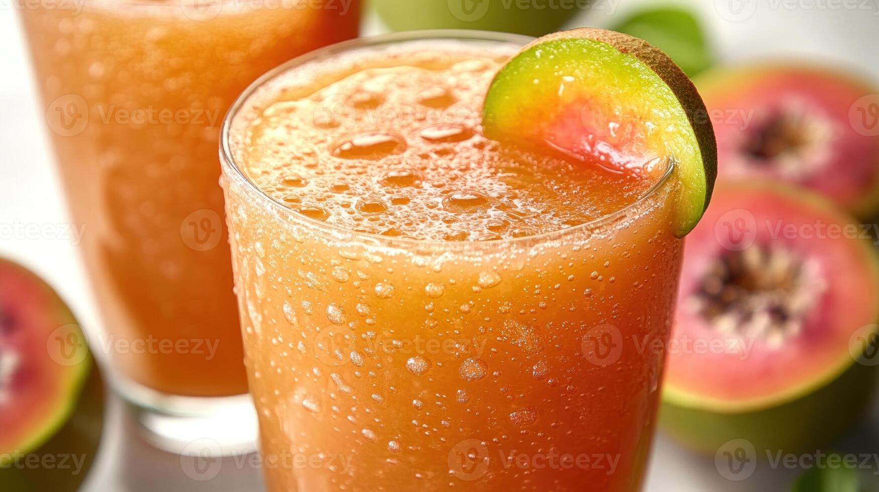 A vibrant glass of guava juice rests on a table with fresh guavas nearby photo
