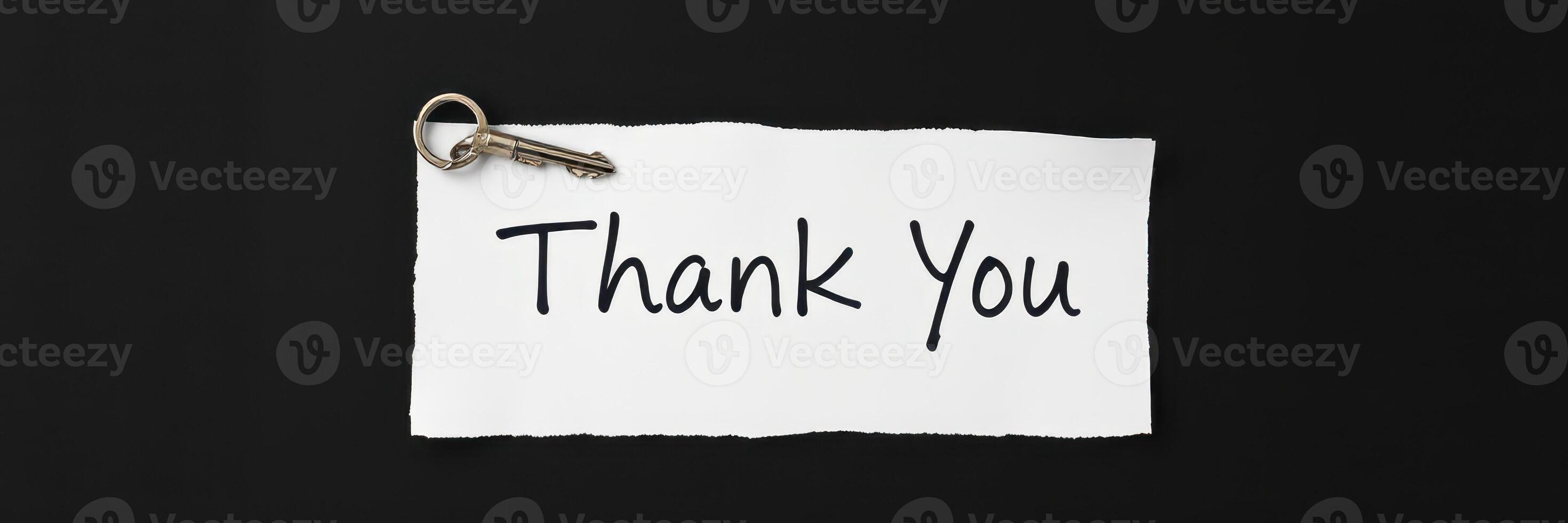 Expressing gratitude with a handwritten note attached to a key on a dark surface photo