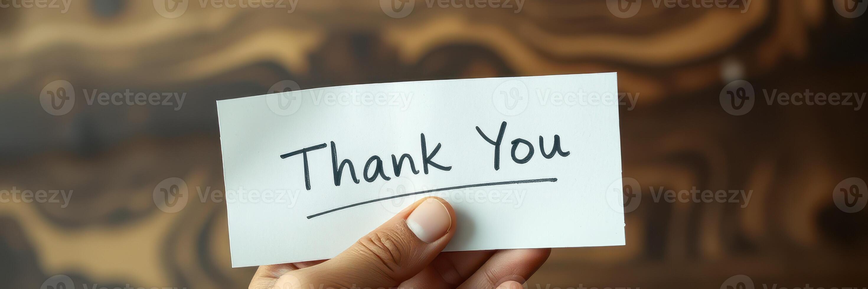 Hand holding a thank you note against a wooden background expressing gratitude in a warm and inviting atmosphere photo