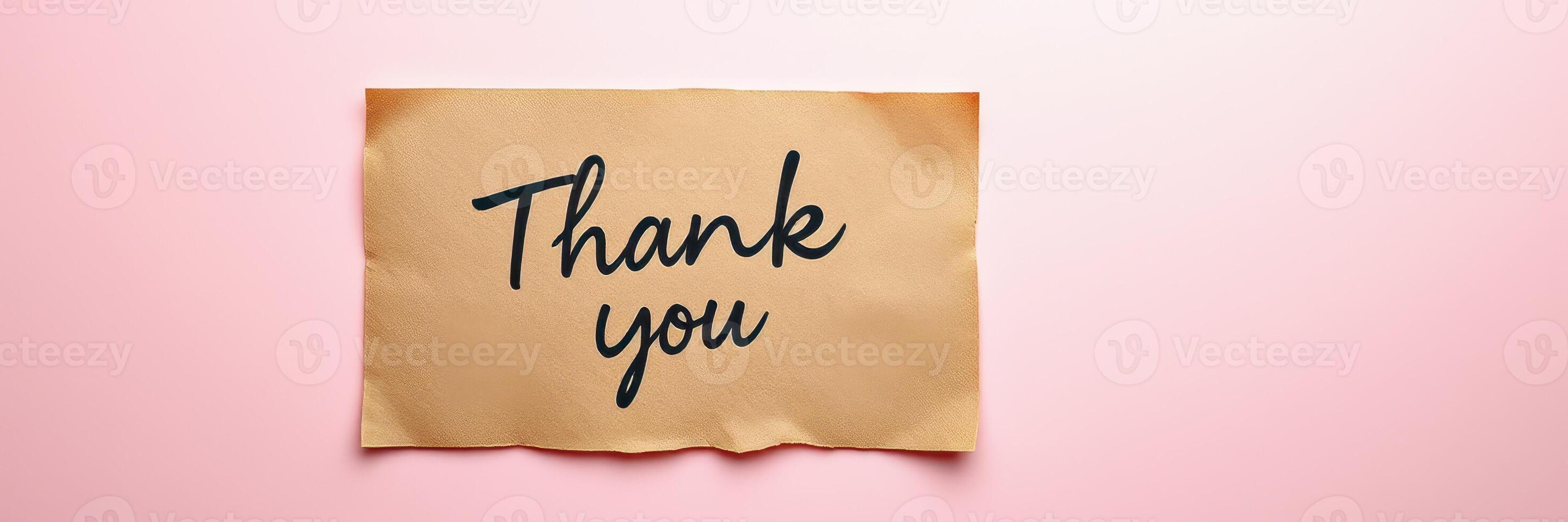 Gratitude expressed through a handwritten note on brown paper set against a soft pink background photo