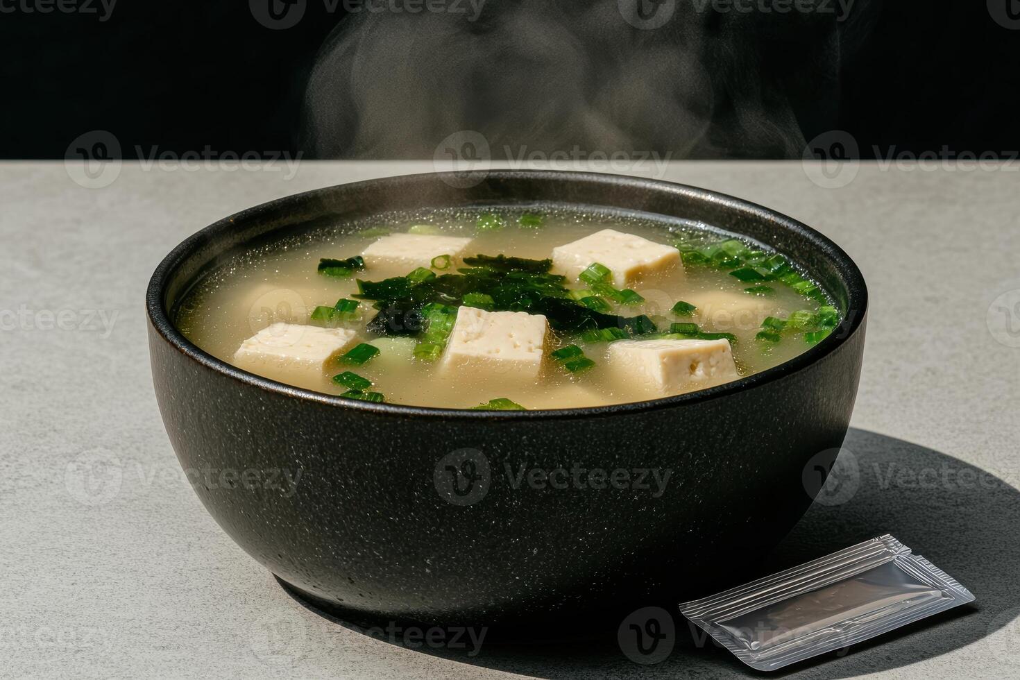 Steaming bowl of miso soup with tofu and seaweed photo