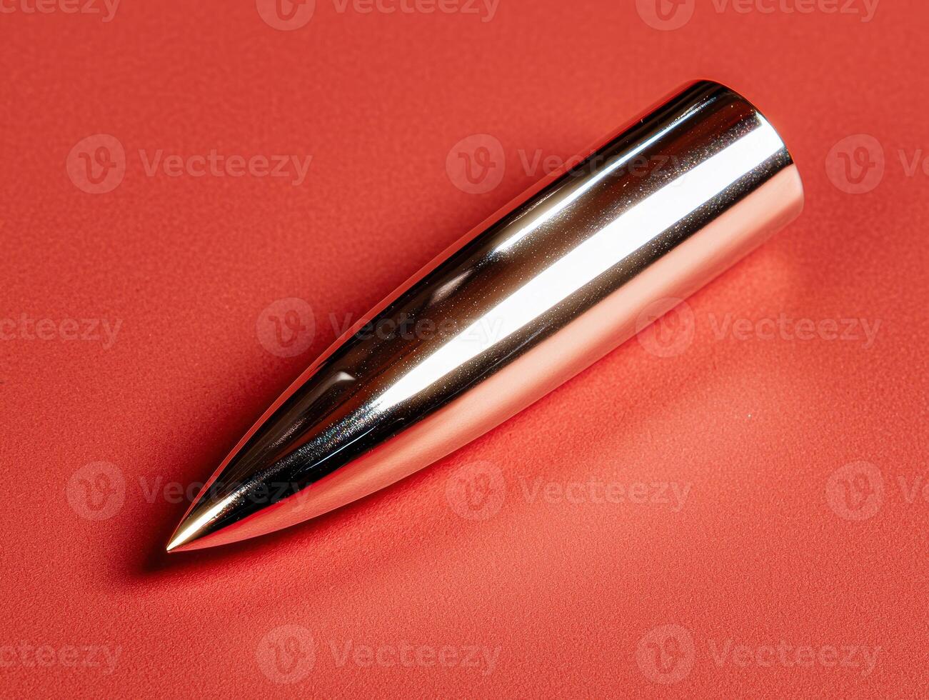 Metallic bullet shaped object on red background photo