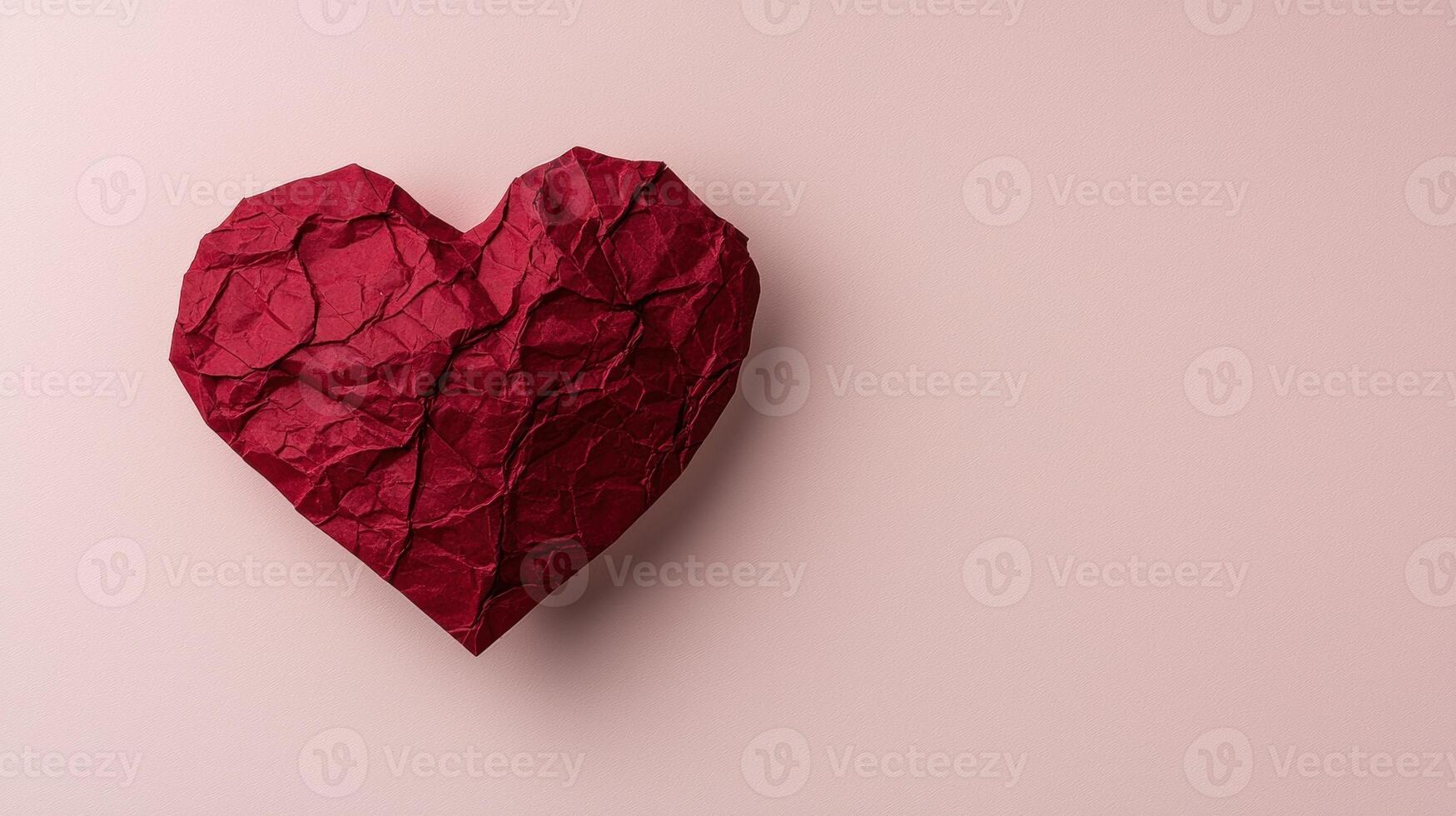 Red crumpled paper heart on pink background photo