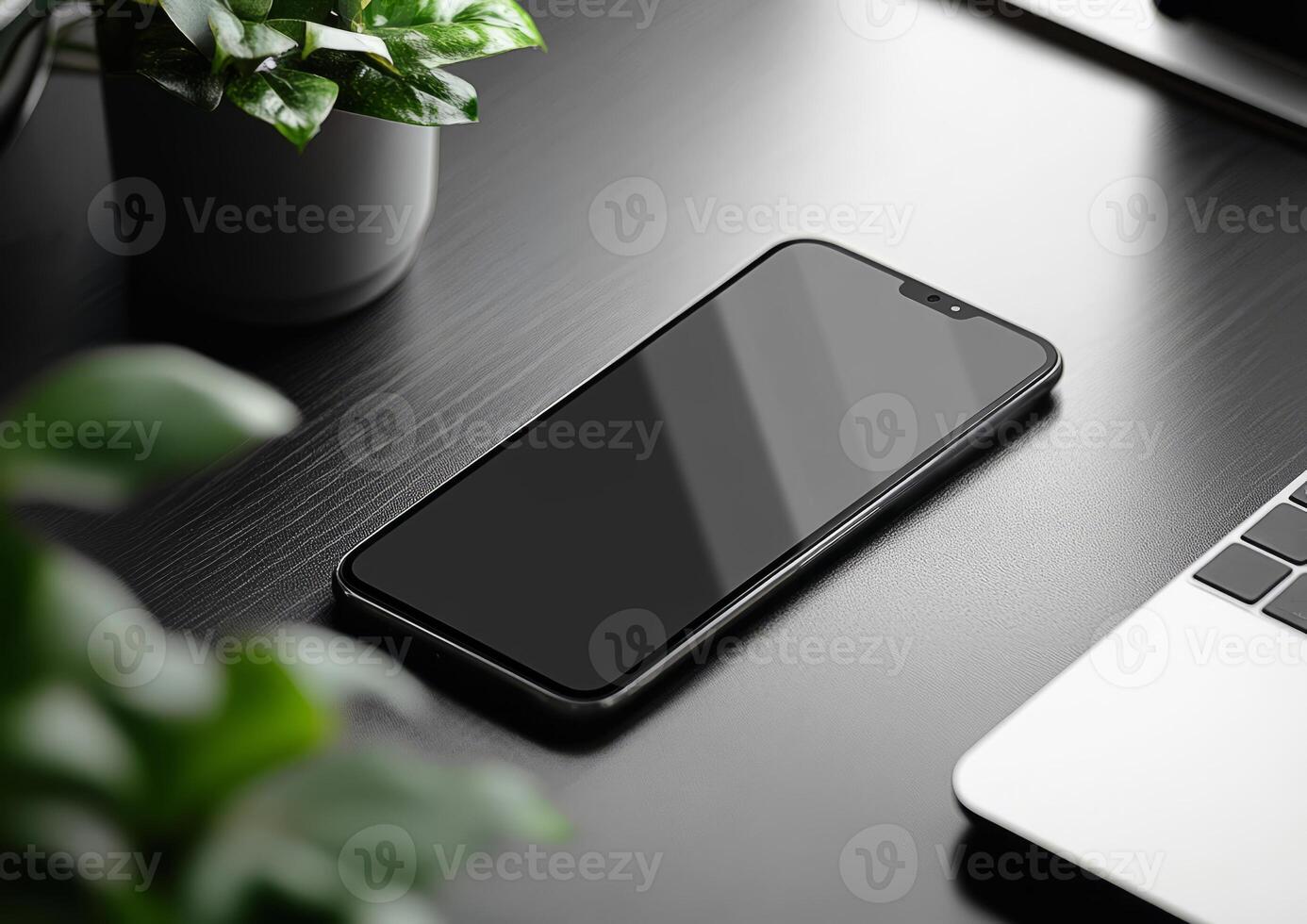 Smartphone lying on desk with plants and laptop in home office setup photo