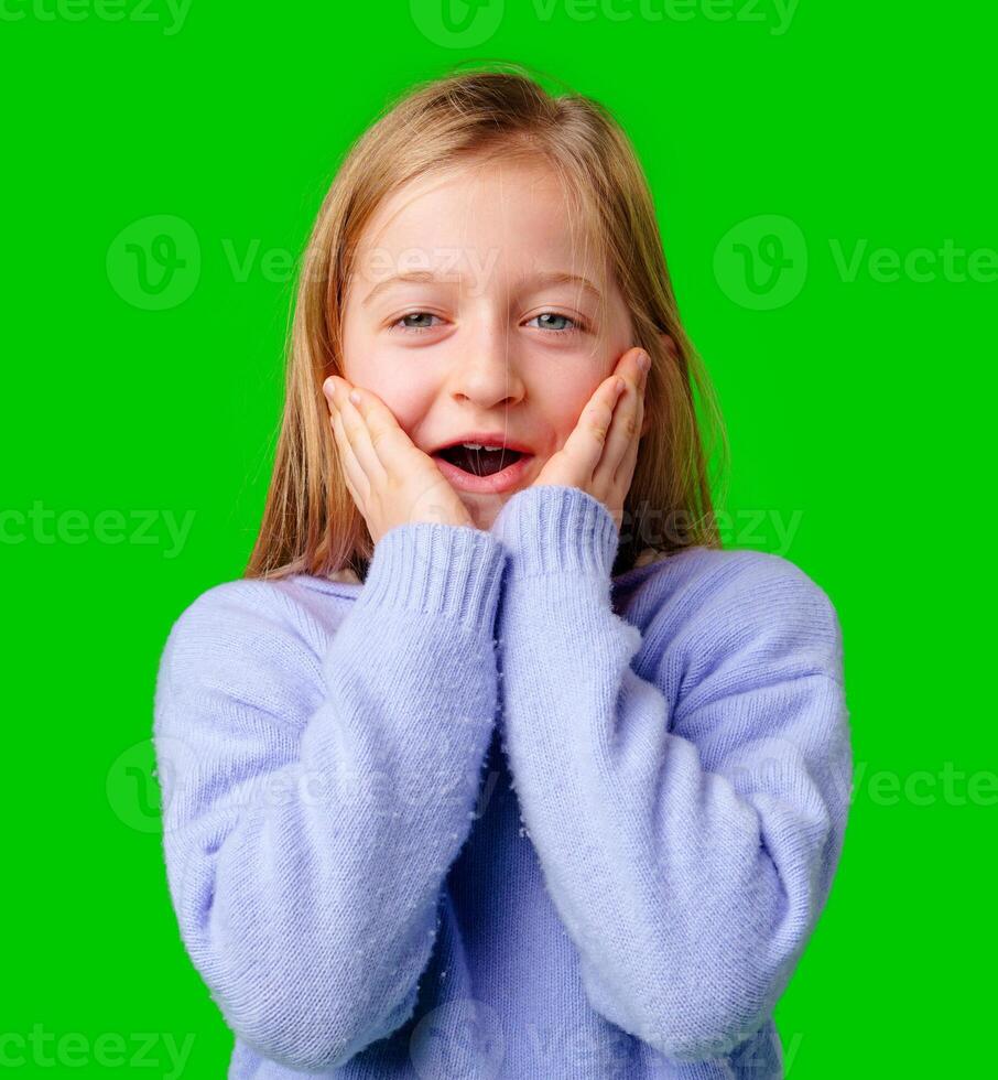 A young girl expresses surprise while smiling, with bright green background photo