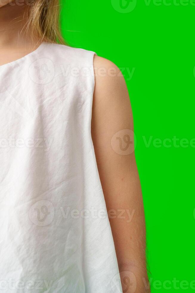 A child stands in front of a bright green background close up photo