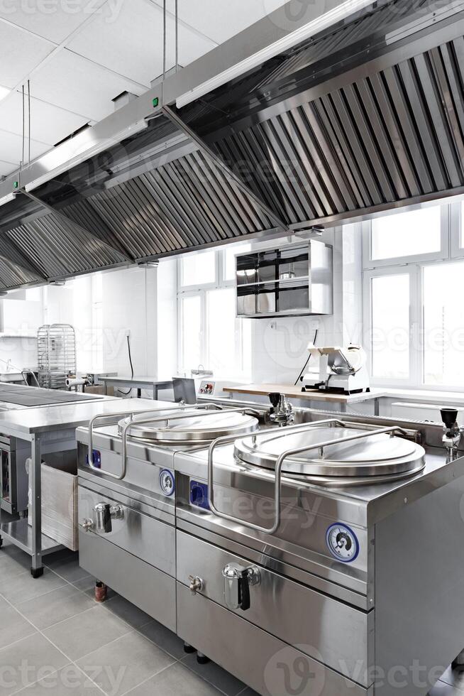 Modern commercial kitchen equipped with stainless steel appliances and ventilation system for culinary operations photo
