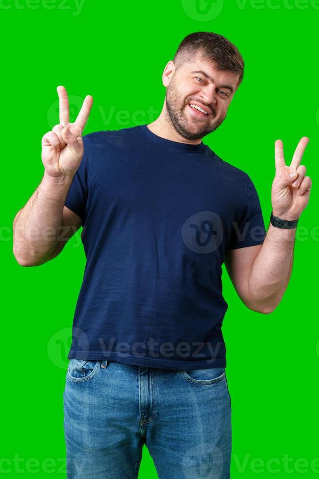 Man smiling and giving peace signs while standing against a bright green backdrop photo