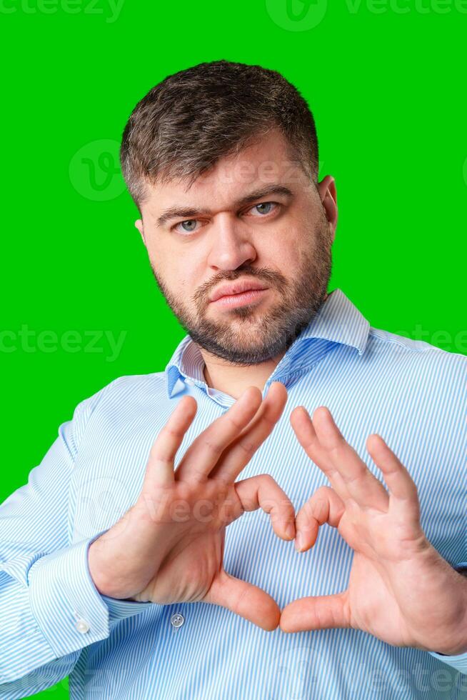 A man forming a heart shape with his hands against a vibrant green background photo