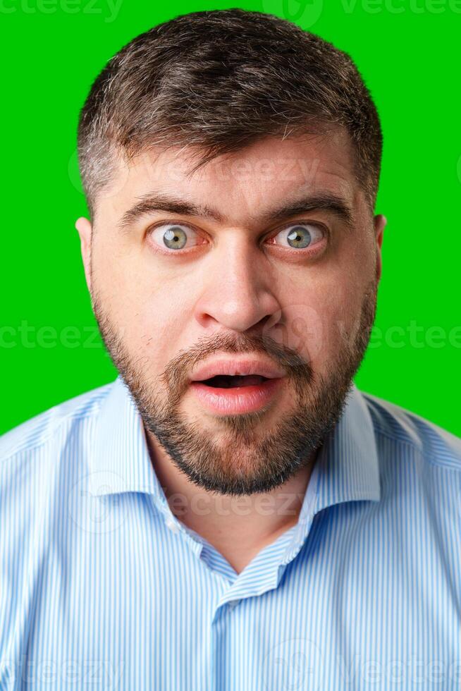 Surprised man with wide eyes and an open mouth against a bright green background photo