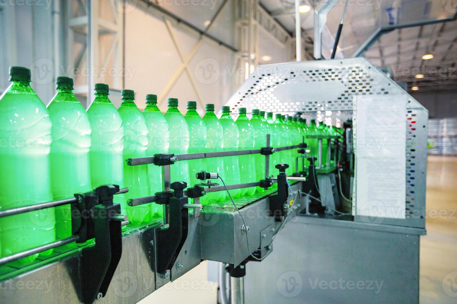 Bottling process in a factory with green plastic bottles moving along a conveyor belt photo