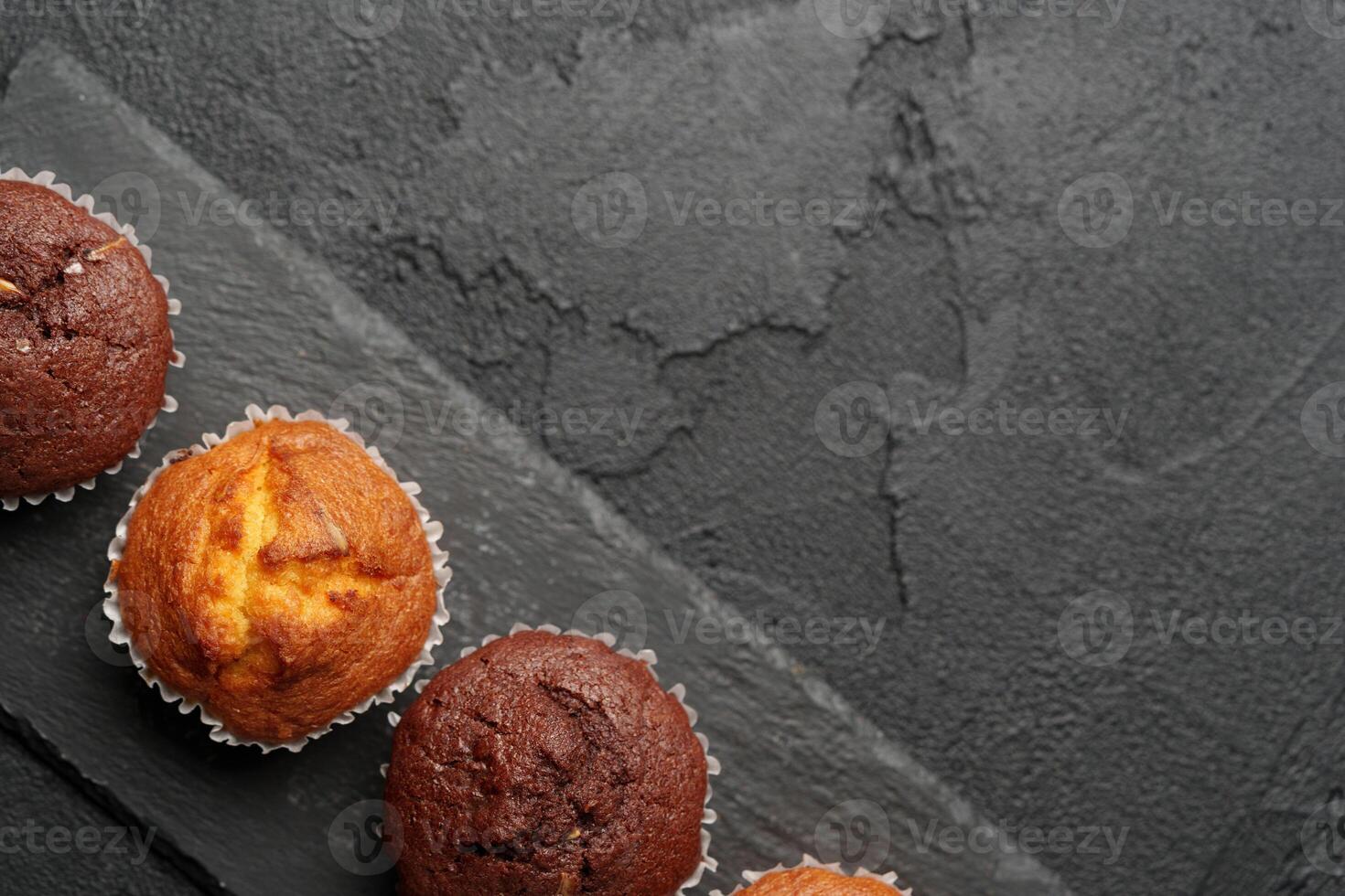 Freshly baked muffins displayed on a dark slate surface, showcasing a variety of flavors and textures inviting a delicious treat photo