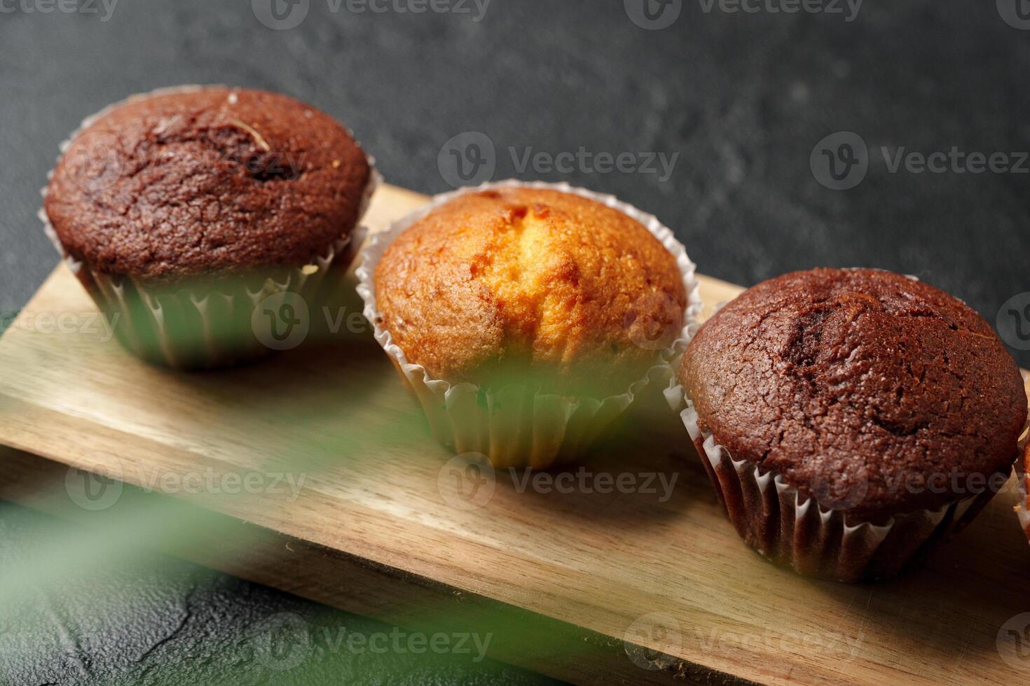 Freshly baked muffins displayed on a wooden board in a cozy setting with soft lighting photo