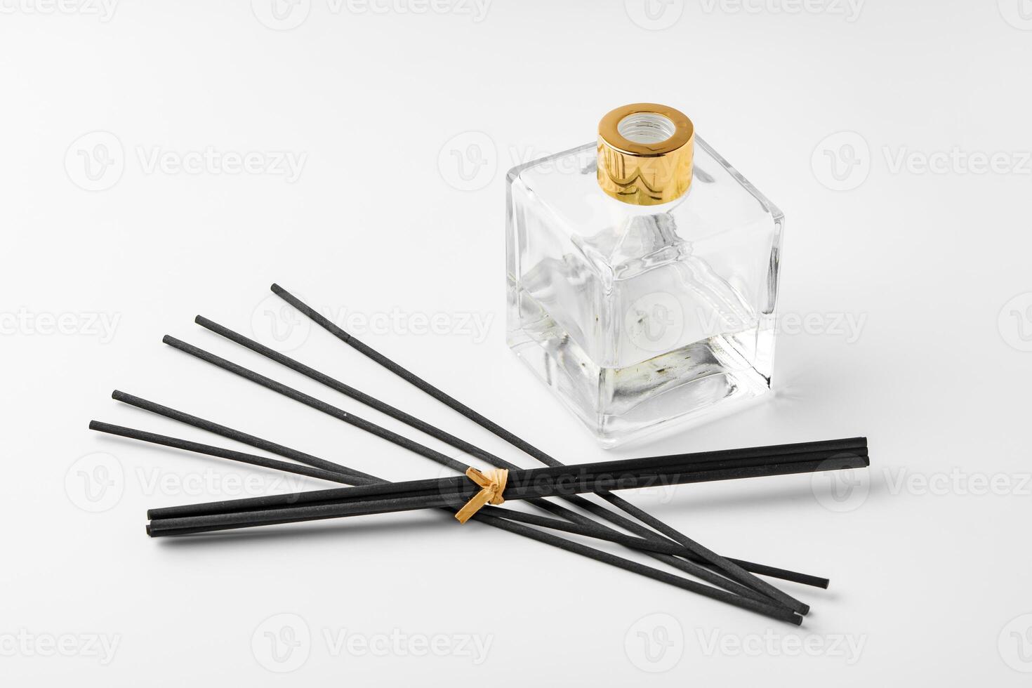 A minimalist display of essential oil and black diffuser sticks on a clean white background photo