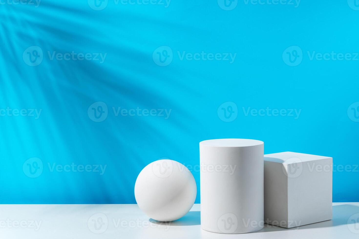 Three geometric shapes arranged on a table against a bright blue background during daytime lighting photo