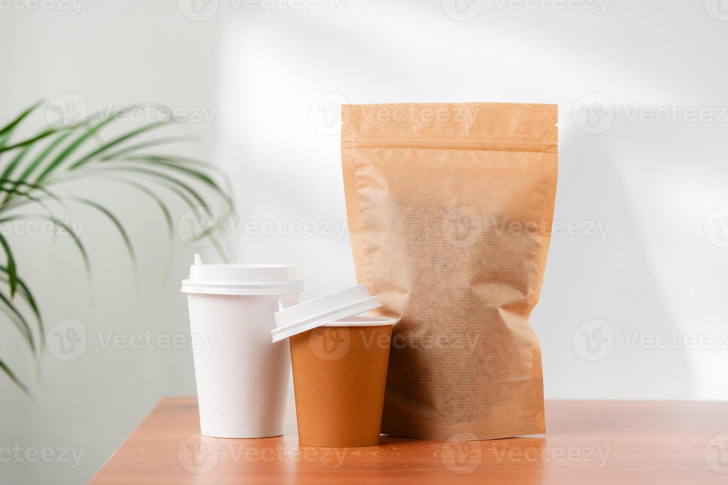 Three beverage containers and a paper bag on a wooden table photo