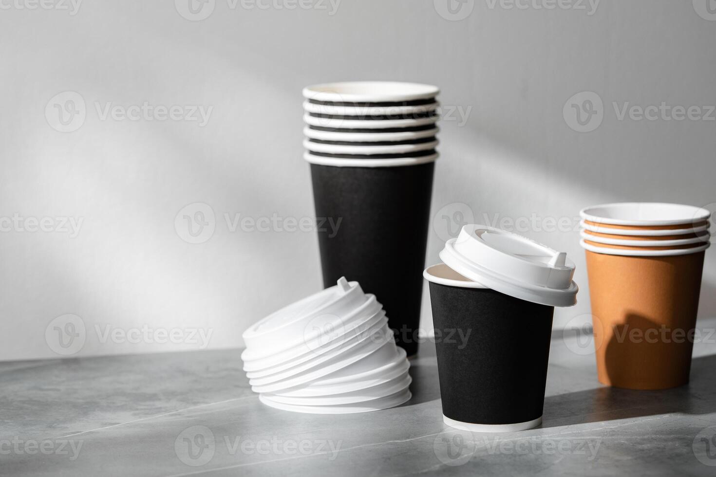 Stack of coffee cups in various colors with lids on a gray surface photo