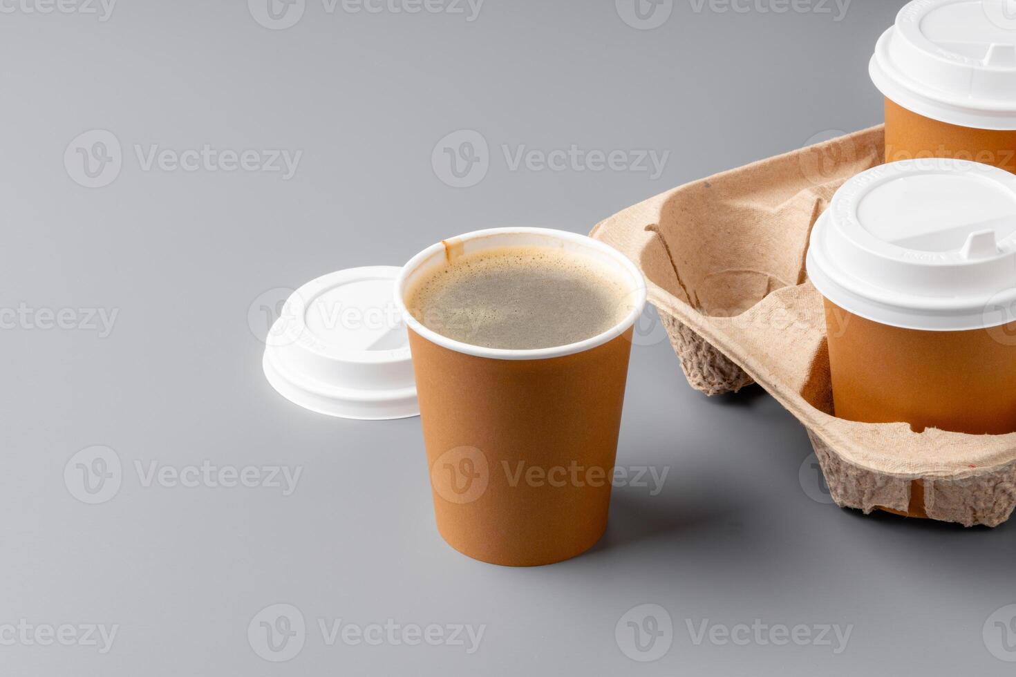 Warm coffee in a brown paper cup on a gray surface with a tray photo