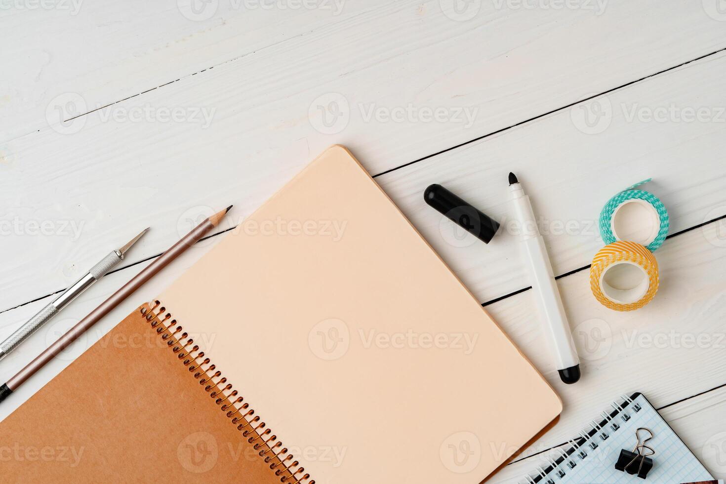 Creative workspace with open notebook, stationery, and decorative items on a wooden table photo