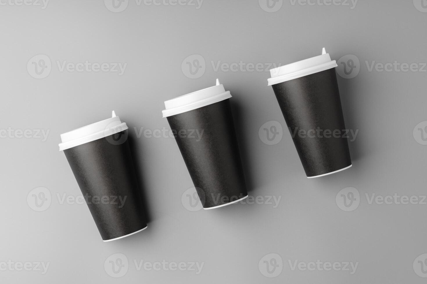 Black disposable cups arranged on a gray surface with white lids, creating a look suitable for a coffee shop setting photo