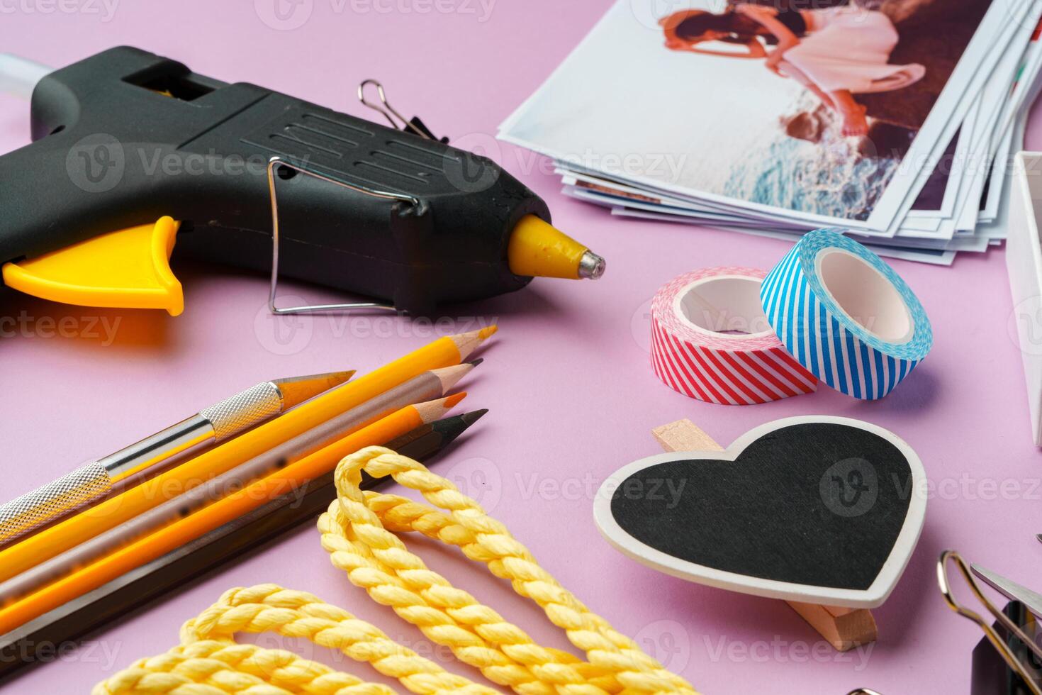 Crafting supplies arranged on a pink background, including glue gun, scissors, and decorative items for DIY projects photo