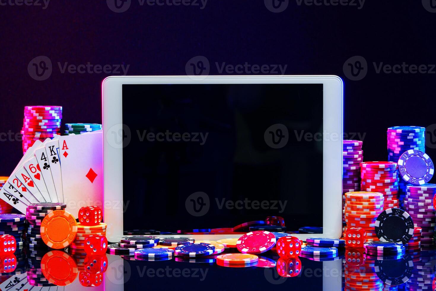 A gaming tablet surrounded by colorful poker chips at a casino table during a night gambling session photo