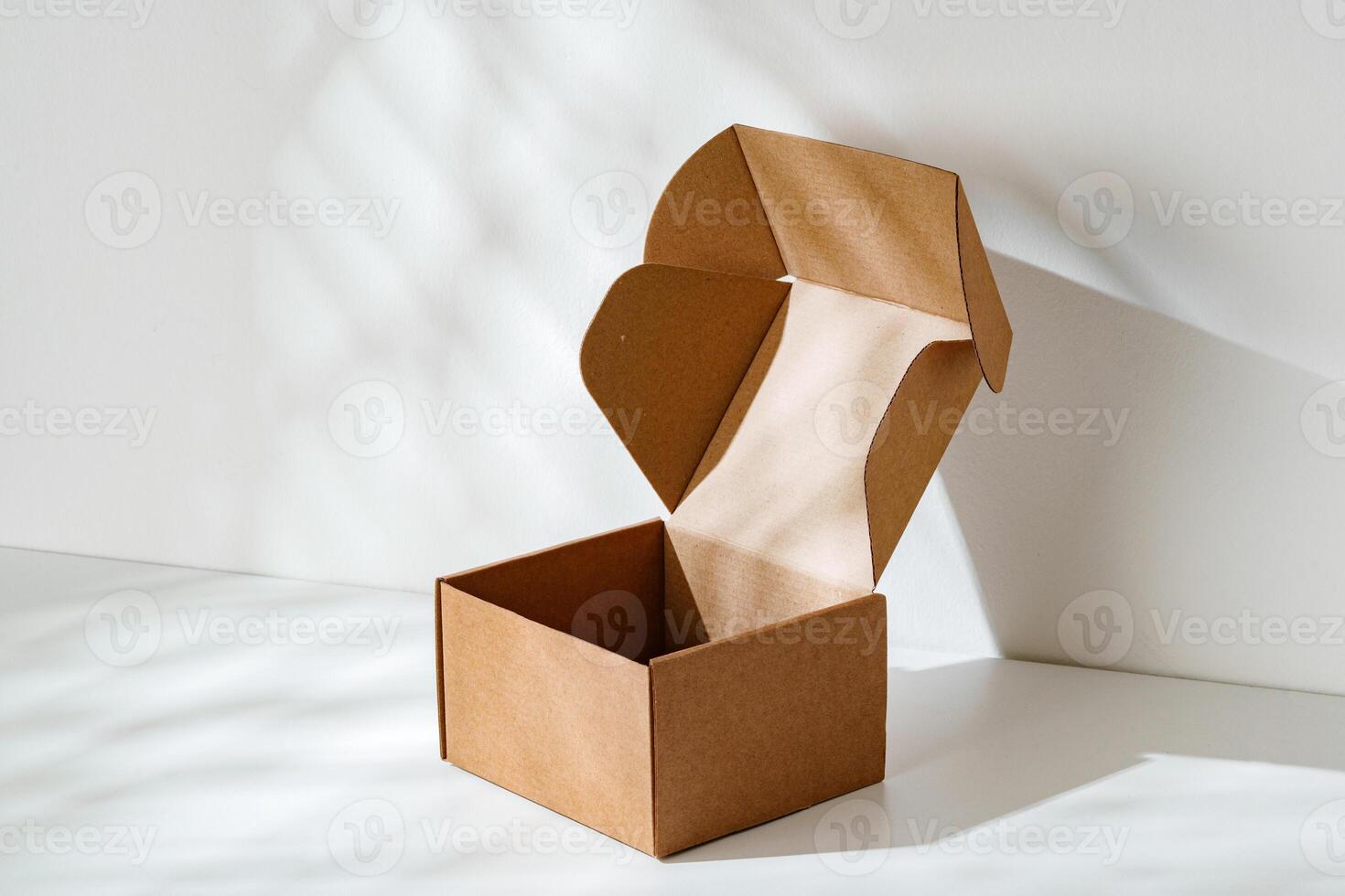 An open cardboard box rests on a bright white surface with soft shadows highlighting its edges and structure in natural light photo