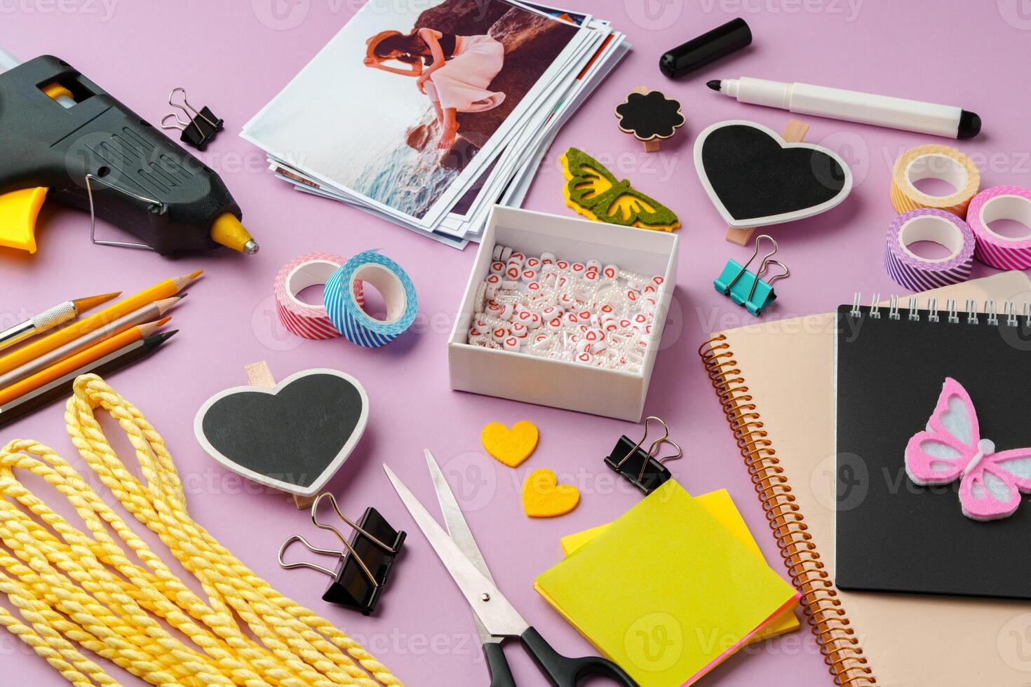 Crafting supplies arranged on a pink background, including glue gun, scissors, and decorative items for DIY projects photo