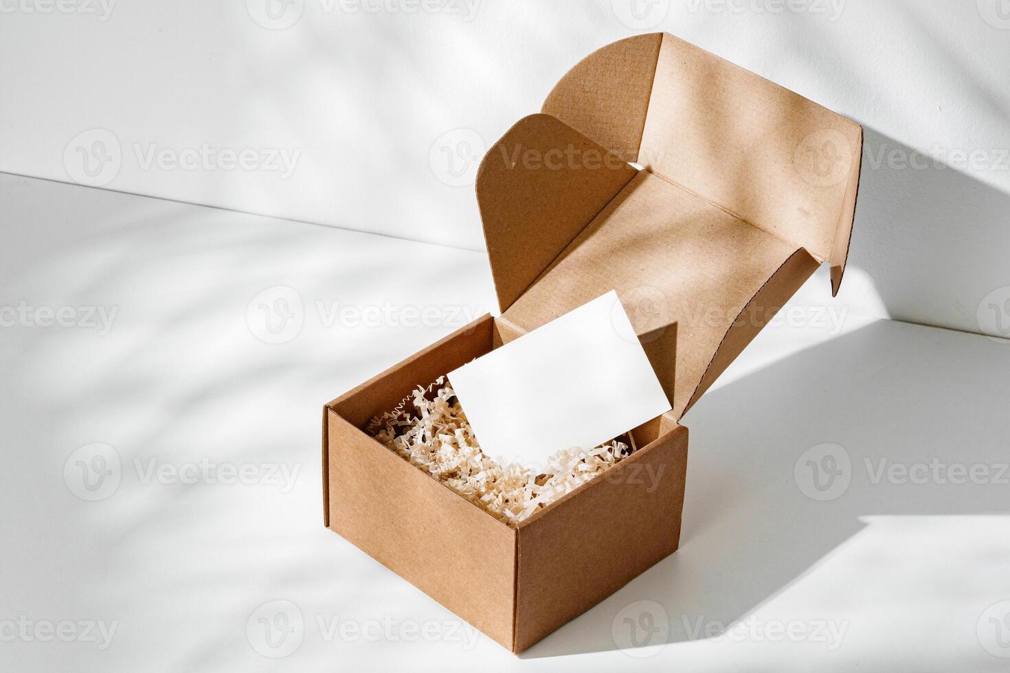 A simple brown gift box with natural filling sits elegantly on a light surface, capturing soft shadows photo