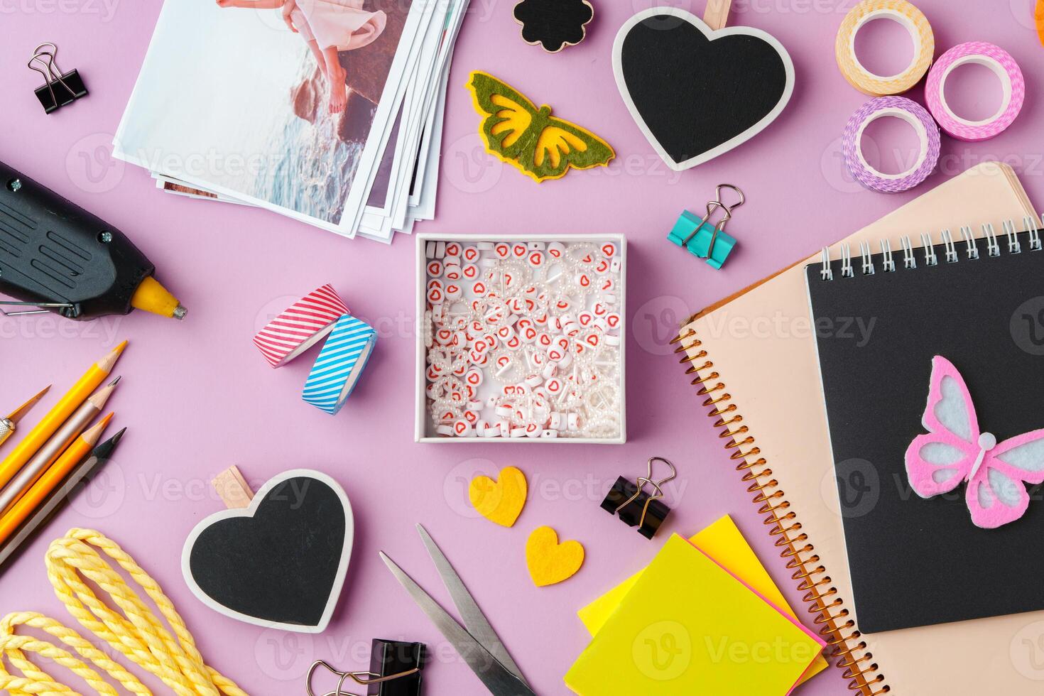 Crafting supplies arranged on a pink background, including glue gun, scissors, and decorative items for DIY projects photo