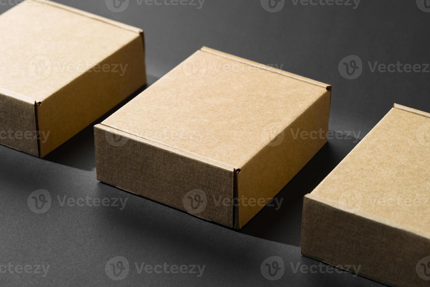 Various sizes of brown cardboard boxes arranged on a black surface with soft lighting effects during the day photo