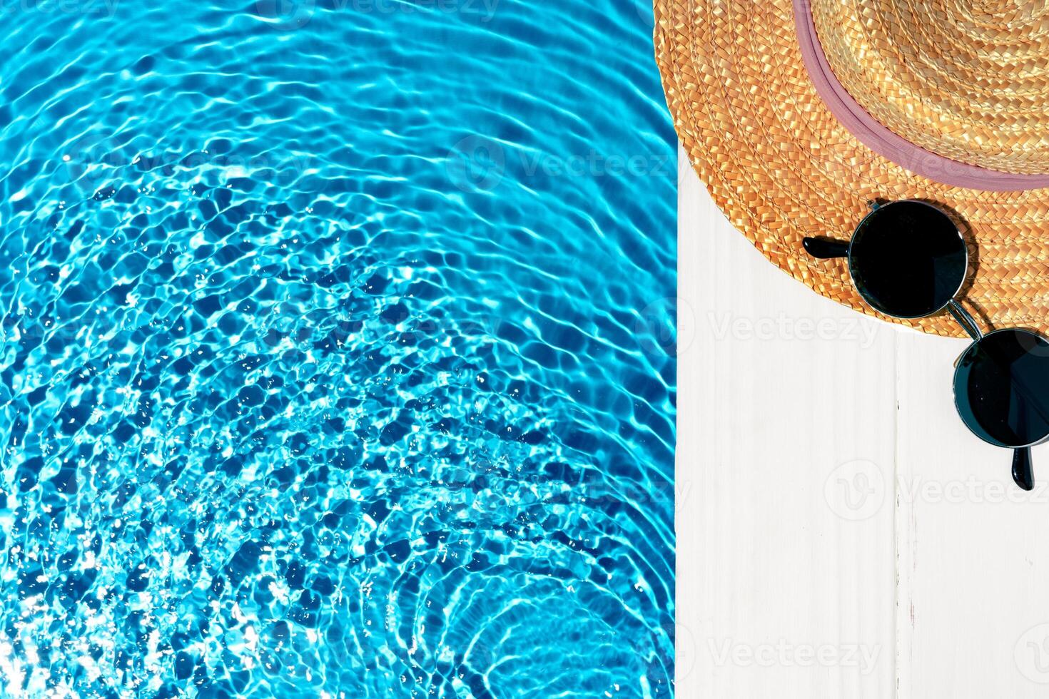Bright summer day by the pool with sparkling water and stylish sunhat resting nearby on a wooden deck photo