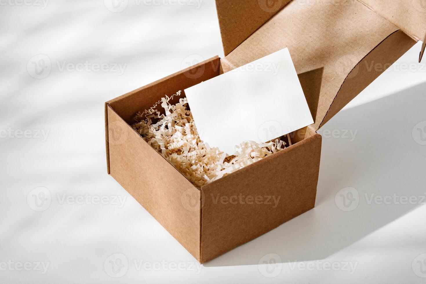 A simple brown gift box with natural filling sits elegantly on a light surface, capturing soft shadows photo