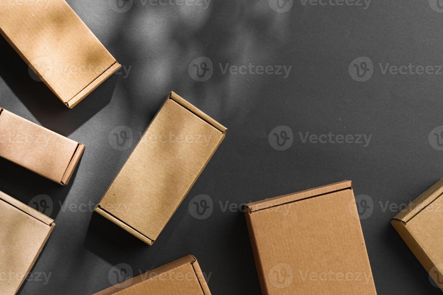 Various sizes of brown cardboard boxes arranged on a black surface with soft lighting effects during the day photo